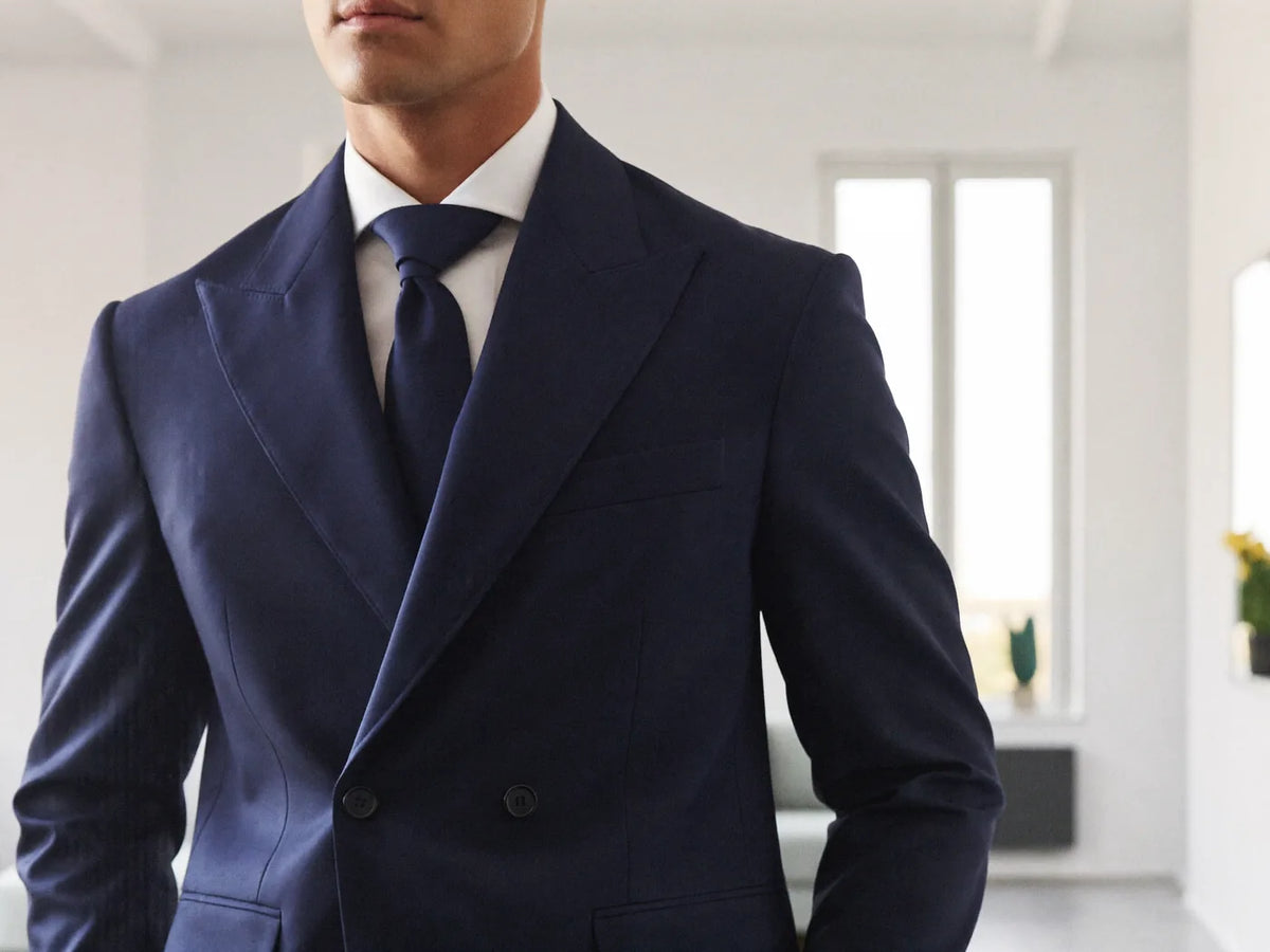 A man wearing a well-fitted navy custom double-breasted wool suit