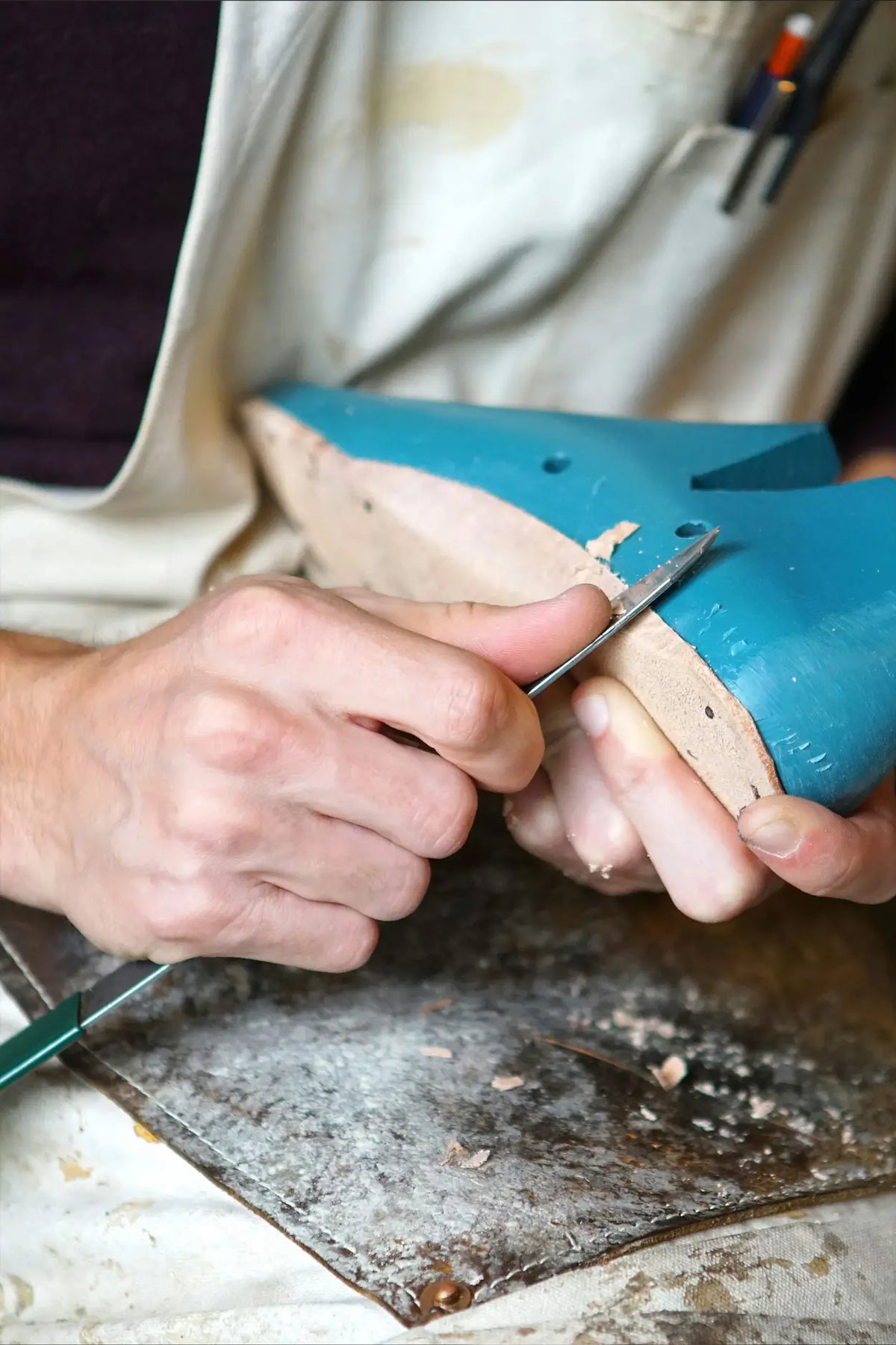 Person working on a shoe with a tool on a wooden surface