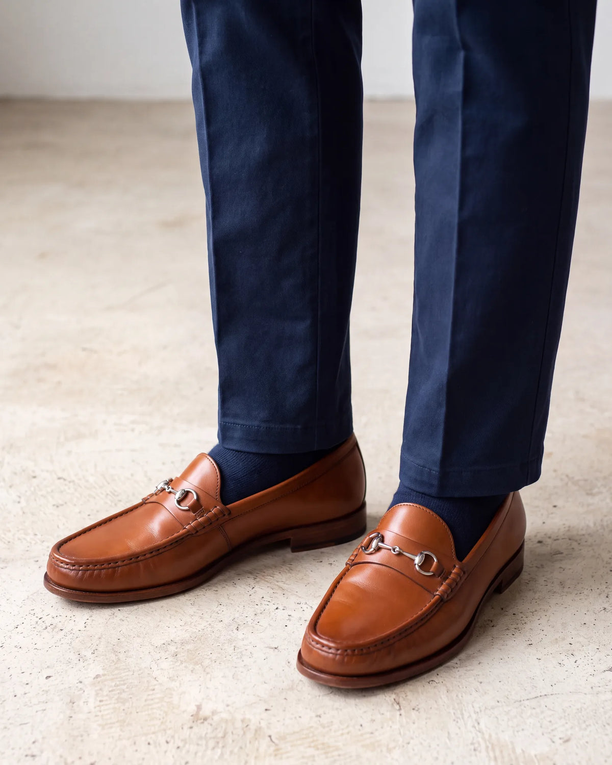 Leave flip-flops and athletic sneakers out. Leather loafers under navy chinos keep the outfit from dropping below the code.