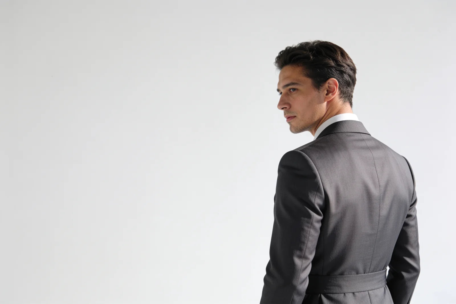 A sharply tailored suit seen from behind showing a clean shoulder line and close drape