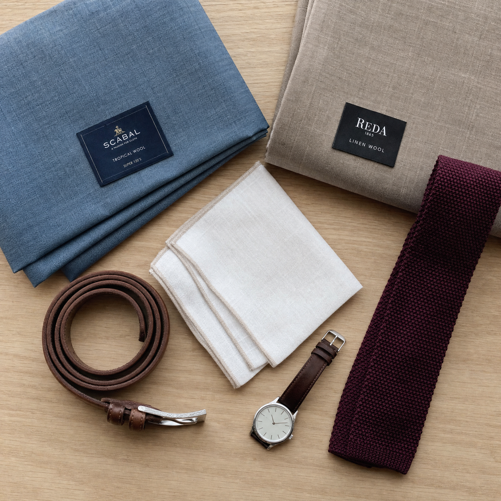 Summer wedding suit fabrics and accessories flat lay with tropical wool, linen blend, silk tie, and leather shoes