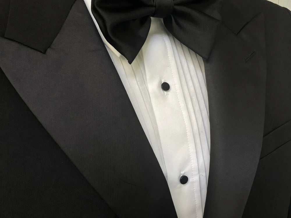 Close-up of a black tuxedo's satin lapel, black bow tie and studded white dress shirt