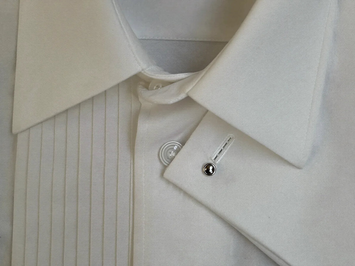 Close-up of a white tuxedo shirt collar, pleated bib front and French cuff with a cufflink
