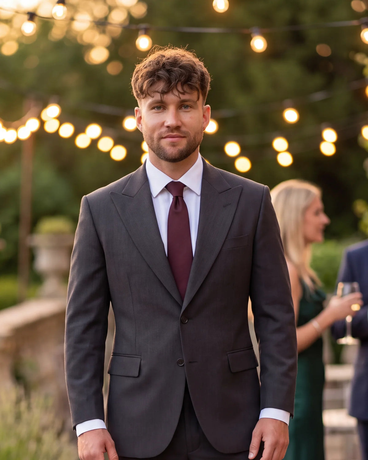 This charcoal suit and burgundy tie fit a cocktail or semi-formal wedding. Navy or gray works too.