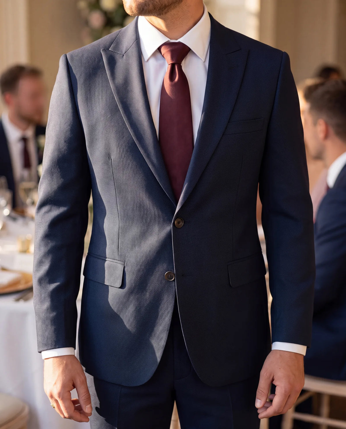 A burgundy silk tie over a white shirt brings the suit up to a formal or evening wedding.