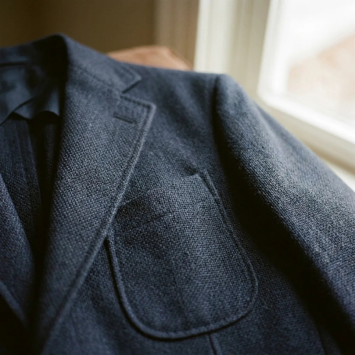 Close view of a textured navy blazer lapel and patch pocket.