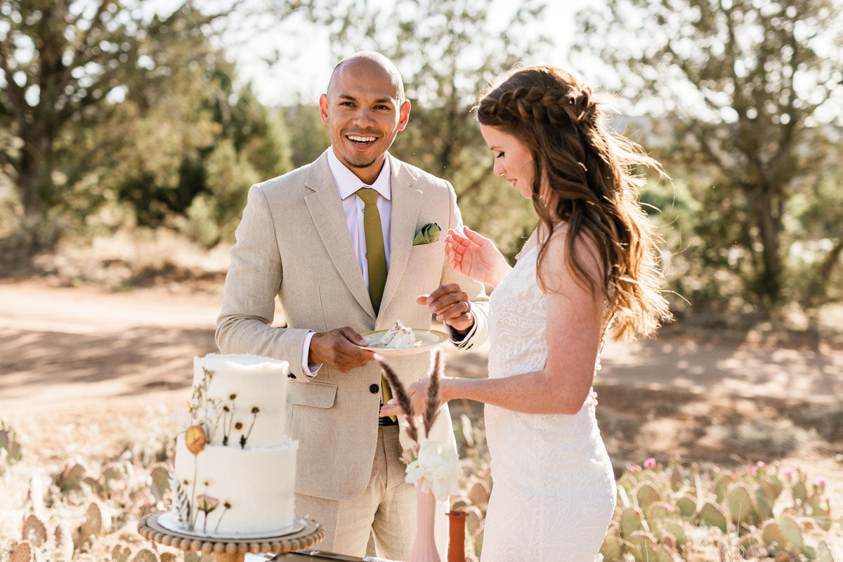 taupe linen suit on a groom with bride eating wedding cake in the savannah