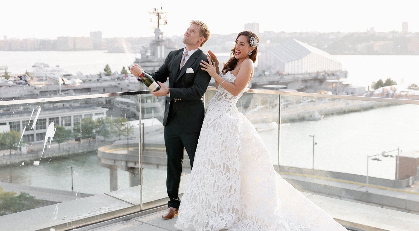 groom in green suit with bride popping champagne