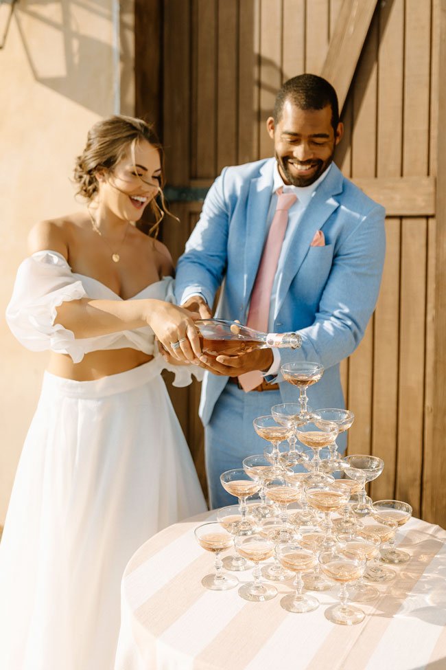 bride and groom pouring champagne into a pyramid of glasses
