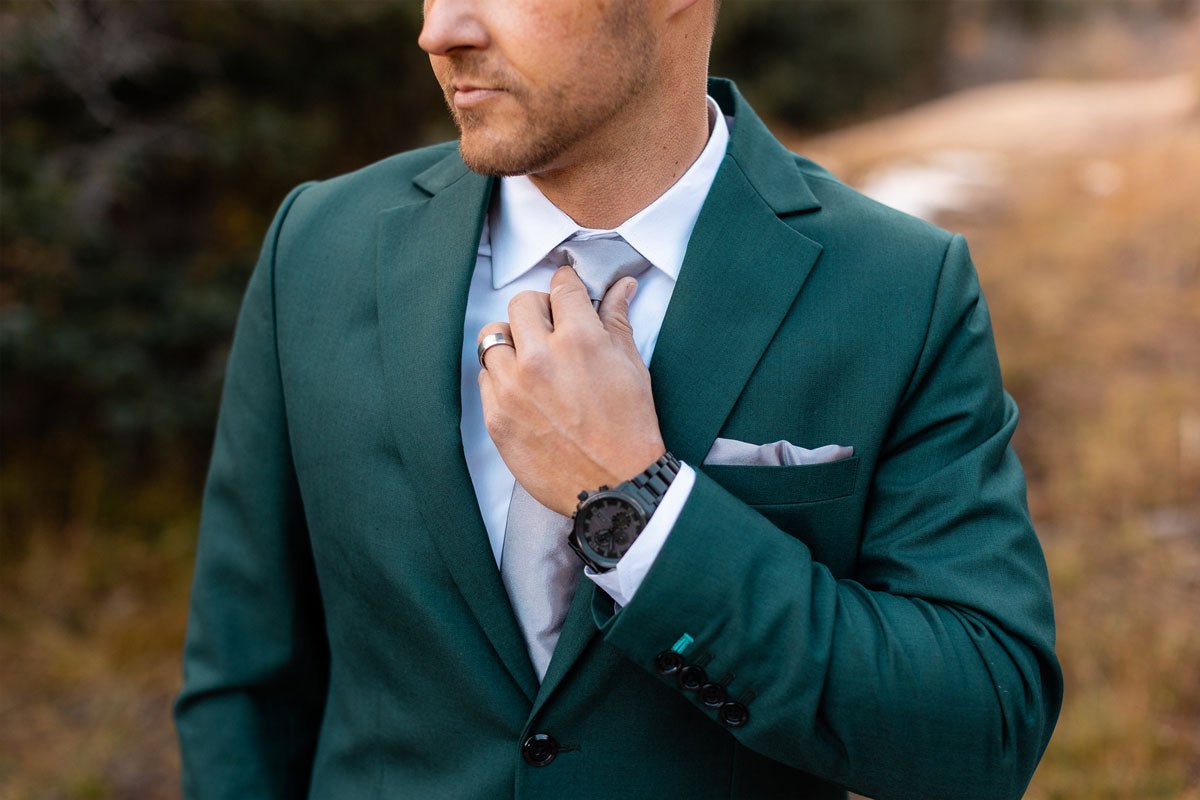 groom popping open a bottle of champagne while his bride looks on