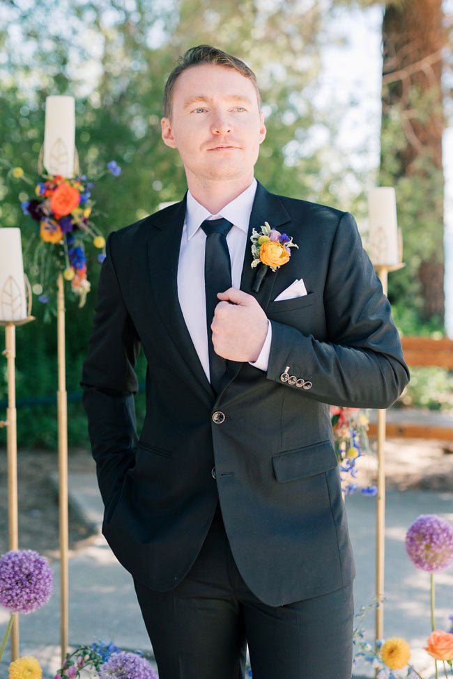 groom standing posing in his black sharkskin wool suit