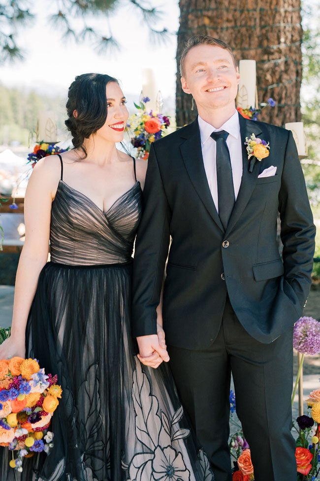 bride and groom holding hands standing  by a tree