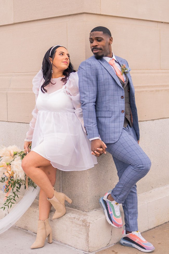 wedding couple holding hands against a building wall