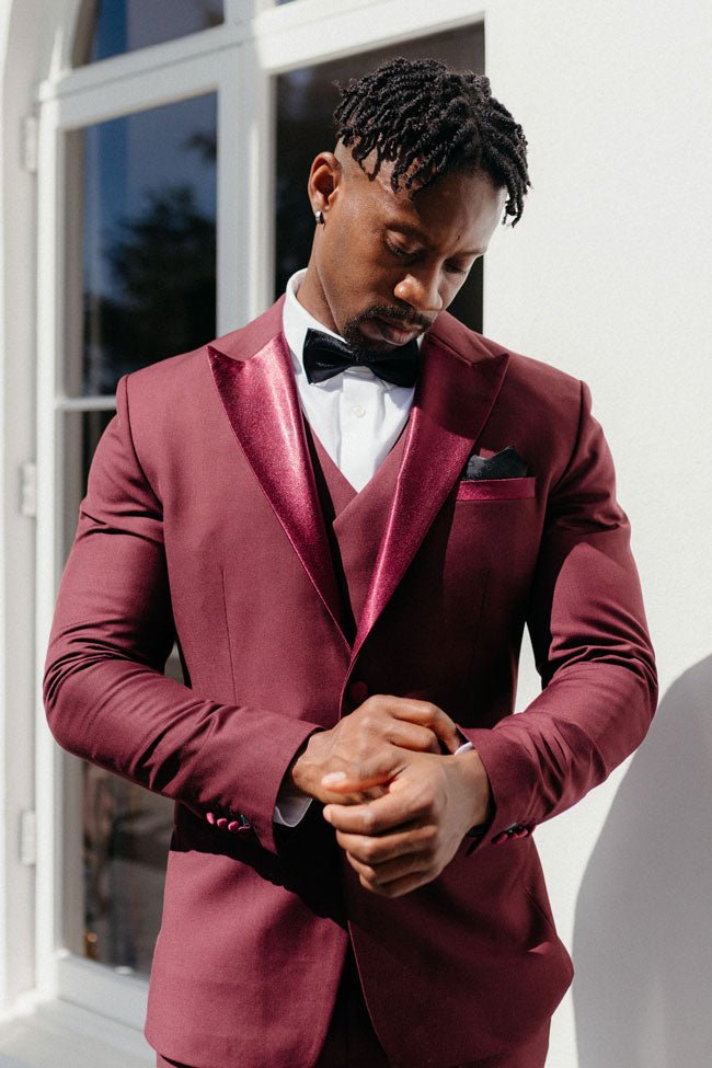 groom fixing his burgundy suit sleeve cuff