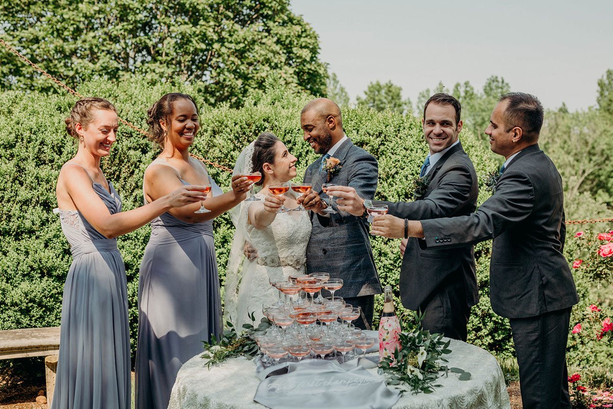 bride and groom being cheered on by the wedding party while they walk through the lawn