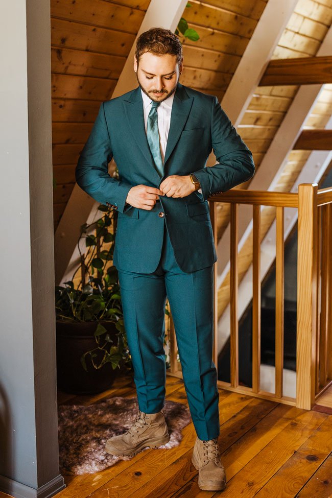 groom standing in his teal wedding suit