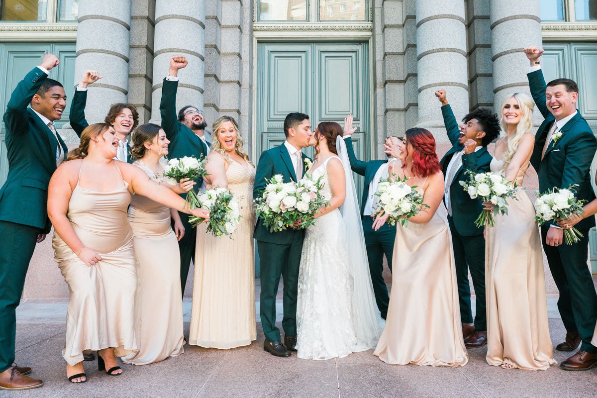 wedding party cheering as bride and groom kiss