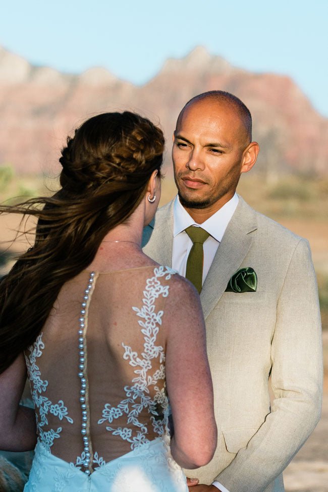 bride and groom sitting together on couch. groom in a grey three piece suit