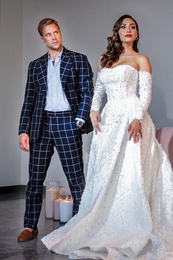 groom popping open a bottle of champagne while his bride looks on