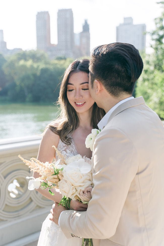 bride and groom embracing in front of a doorway. burgundy tuxedo