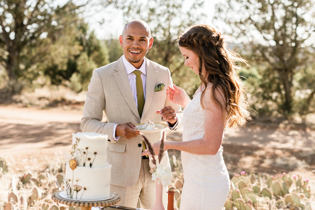 taupe linen suit on a groom with bride eating wedding cake in the savannah