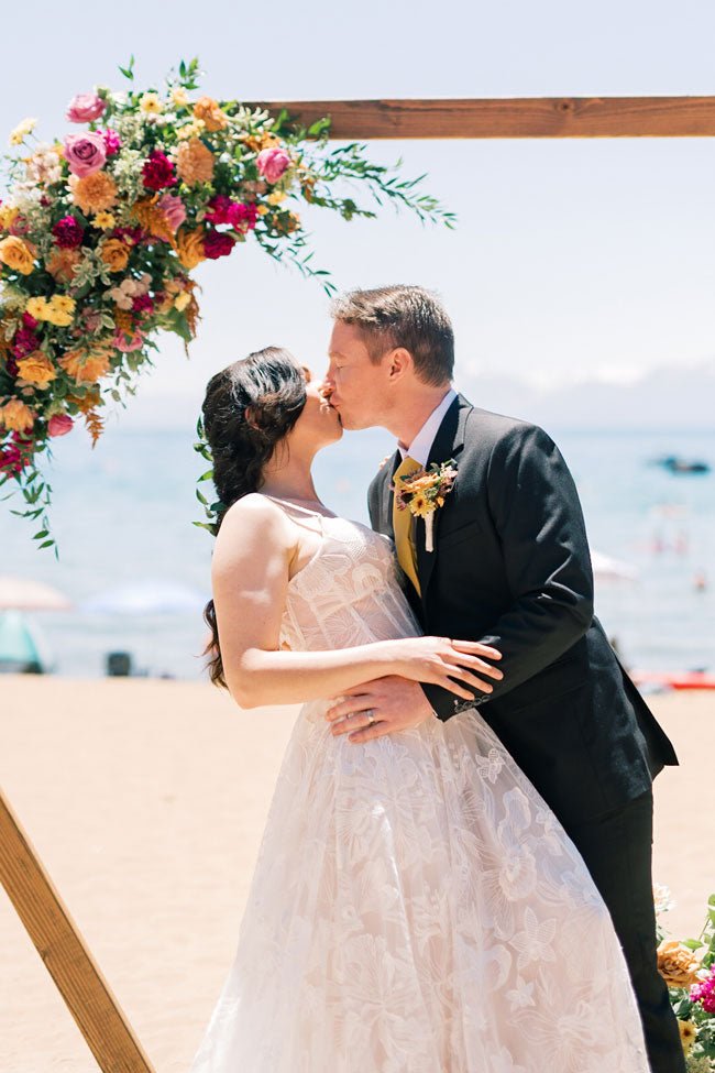 bride and groom kissing at the alter by the beach