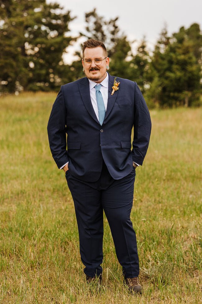groom standing in navy blue stretch suit