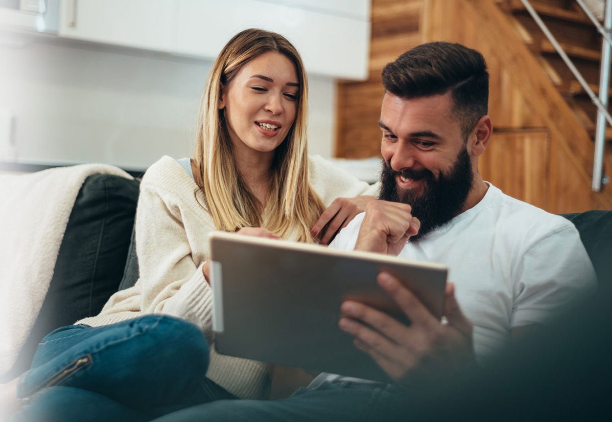 couple on couch looking at tablet