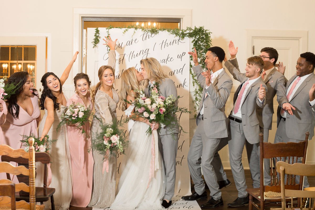 wedding party with bridesmaids and groomsmen posing for a group photo. grey suits.