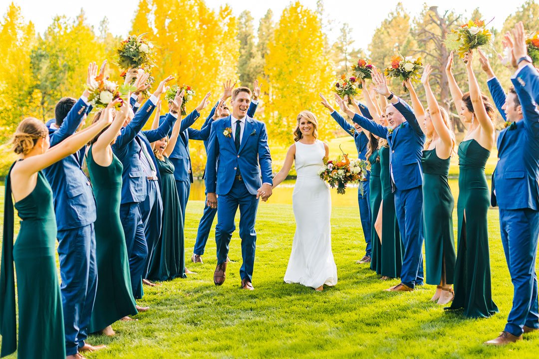 bride and groom being cheered on by the wedding party while they walk through the lawn