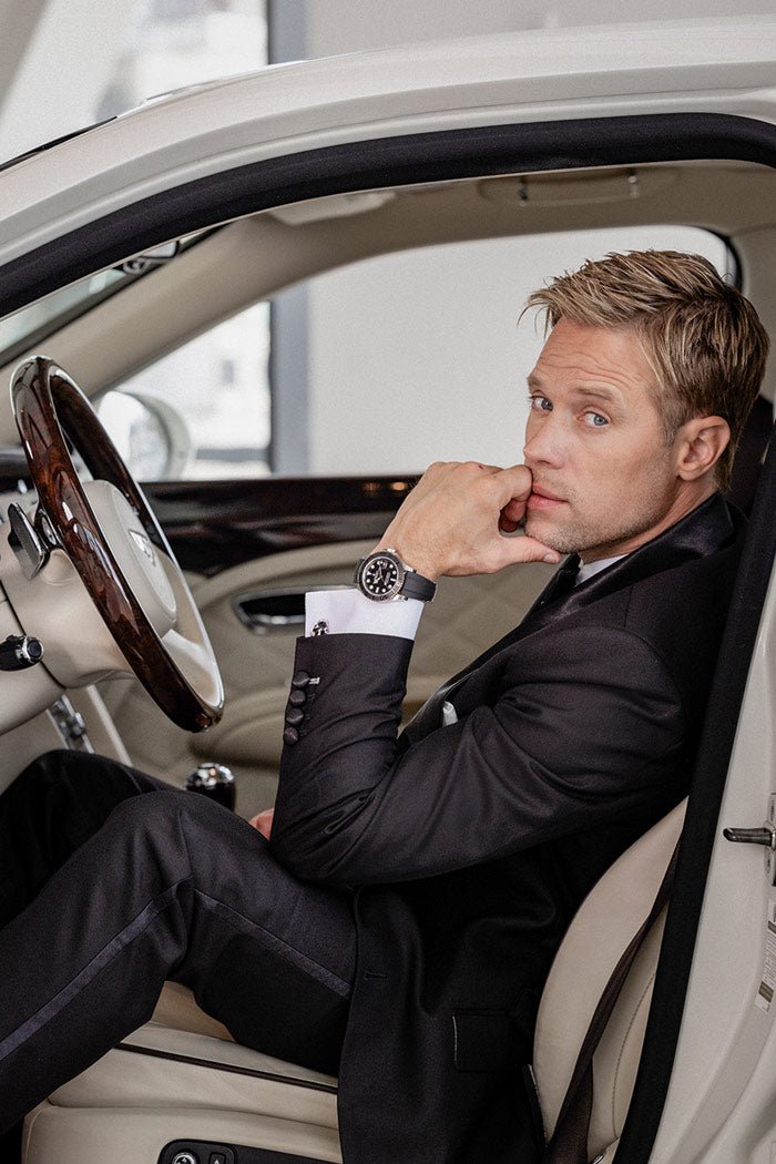 groom popping open a bottle of champagne while his bride looks on