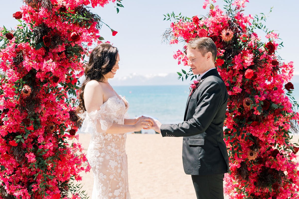 bride and groom standing at the alter in front of the beach, holding hands