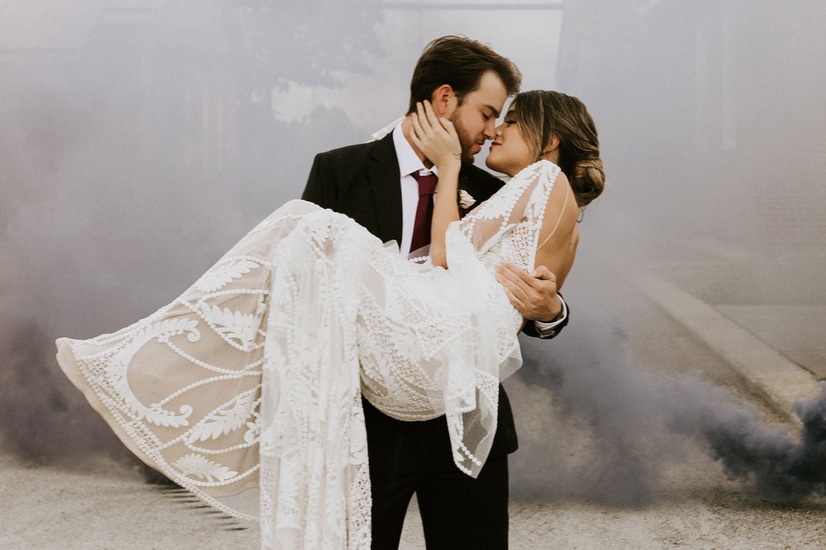 groom holding bride in front of purple smoke